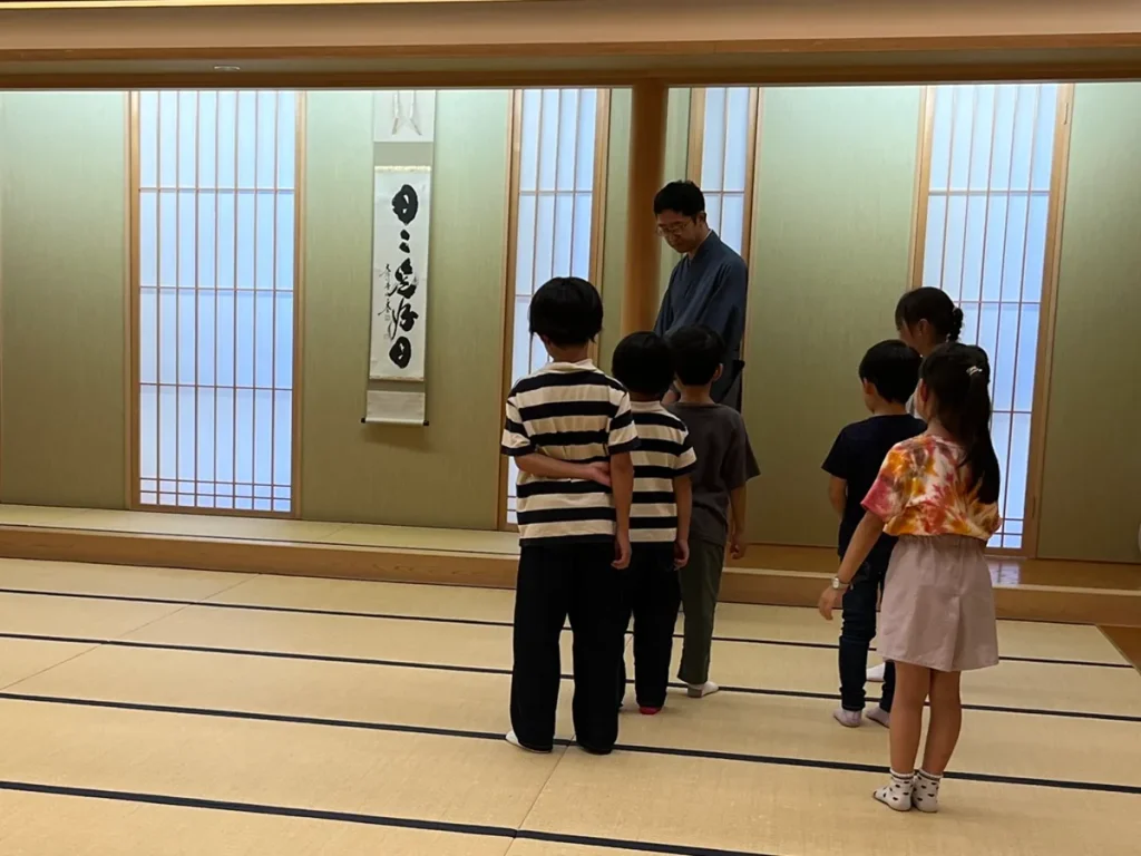 子ども茶道体験会で、講師と一緒に畳の上の歩き方を練習する子どもたち