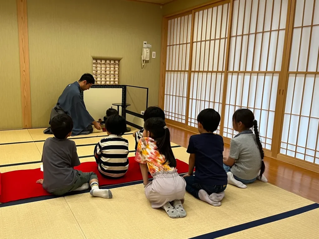 子ども茶道体験会で、講師の点前を見ながらお茶について学ぶ子どもたち