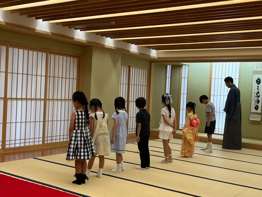 子ども茶道体験会で、講師と一緒に畳の上の歩き方を練習する子どもたち