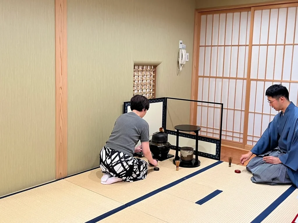 喫茶去で、参加者が講師に見守られながら点前を体験している様子