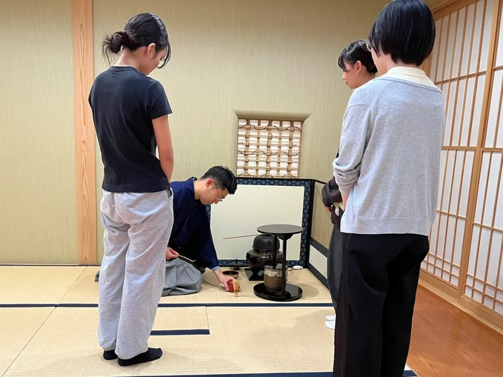 喫茶去で、講師から薄茶点前のやり方や茶道具について説明を受ける参加者
